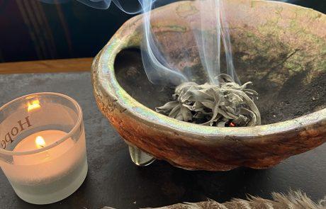 feather, candle and sage burning in bowl