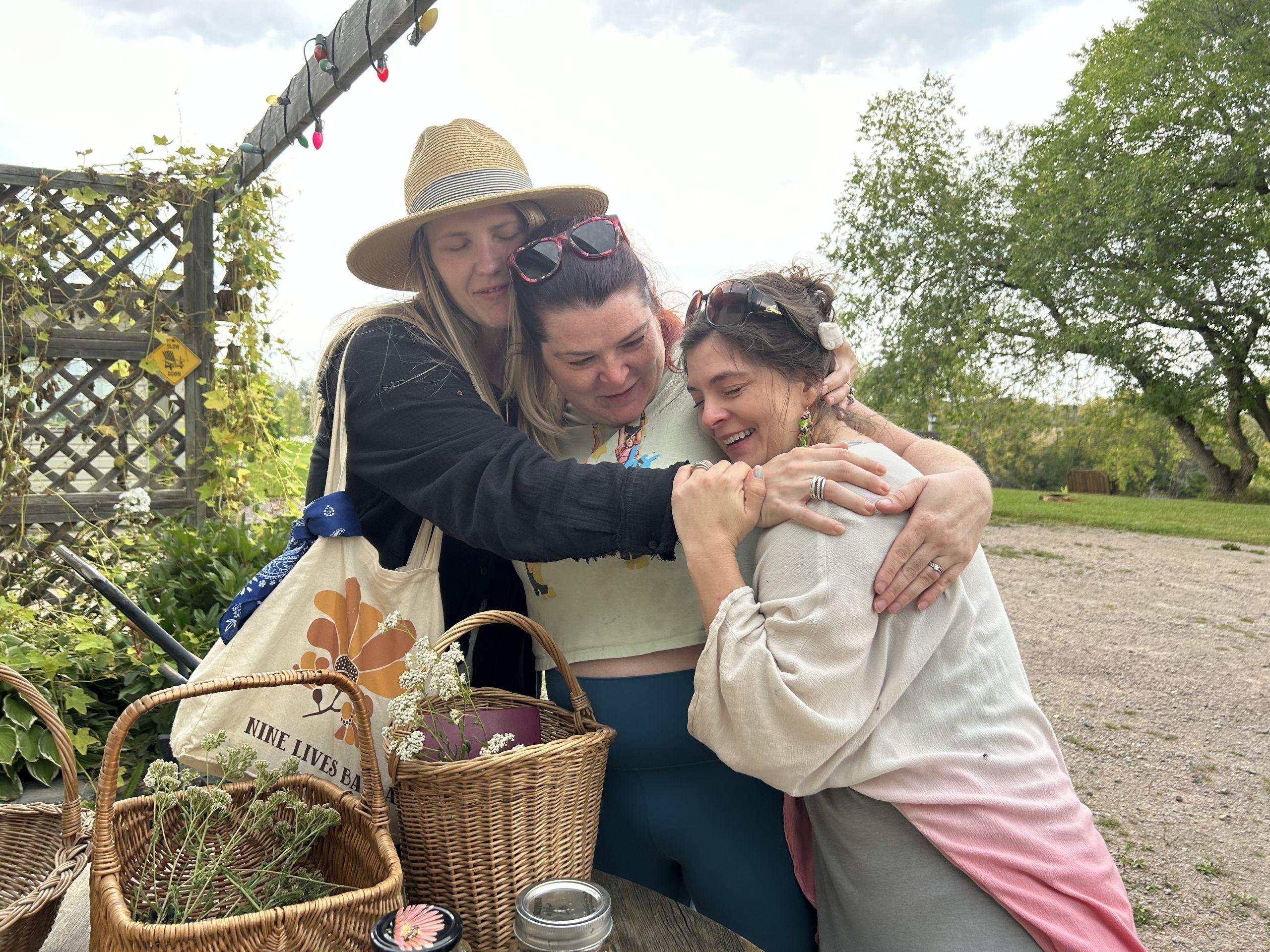 Three women hugging after a plant walk with Jenny.